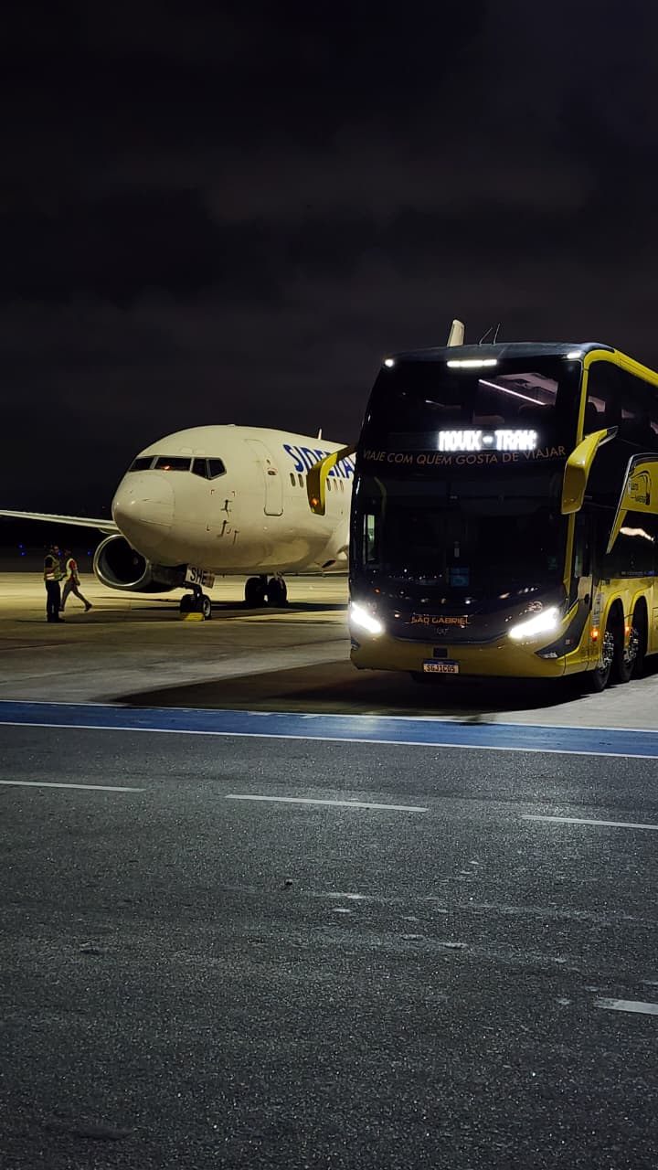 Ônibus leito Movix em transfer de aeroporto, ao lado da aeronave